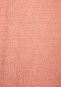 Strukturierter Stoff in sanftem Koralle, mit einem Muster aus erhabenen hexagonalen Formen. Leichter Glanz mit einem subtilen, einheitlichen Erscheinungsbild.