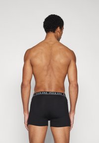 Boxer shorts noirs avec une taille de marque. Le matériau semble lisse, avec un design ajusté qui met en valeur la forme et la structure.