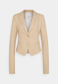 Blazer de mujer ajustado en color beige, con cierre de un solo botón, solapas con muesca y dos bolsillos de ojal en la parte frontal.