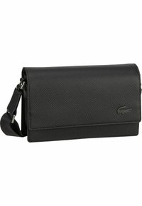 Borsa a tracolla nera con texture, chiusura a patta magnetica e tracolla regolabile. Presenta un logo Lacoste discreto sul davanti.
