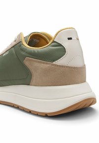 Vue arrière latérale d’une basket verte, beige et blanche avec des détails en daim, une semelle rembourrée et le logo "BOSS" sur le côté.