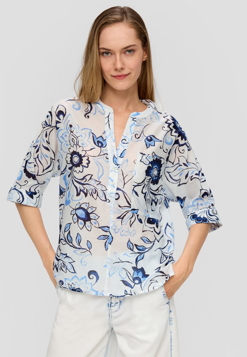 Blouse légère à motif floral bleu clair et blanc. Dotée d'un col mandarin, d'une patte de boutonnage et de manches longueur coude.