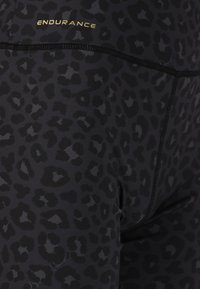 Svarta leggings med ett leopardsmönster i varierande nyanser av svart. Har en subtil guld "ENDURANCE"-logotyp och diskreta sömdetaljer.