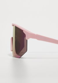 Occhiali da sole sportivi rosa con design angolare, lenti viola gradientate e montatura in plastica. Presentano tempie larghe e dettaglio del logo sul braccio.