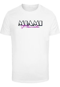 Tricou alb din bumbac cu inscripția 'MIAMI' în litere negre îndrăznețe și 'Florida' în cursiv roz, având un accent geometric în design.