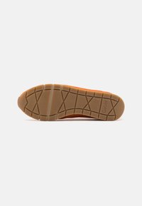 Sneaker sole with textured rubber, orange accents, and a flexible design. Features a tread pattern for grip and marked branding.