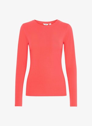 Pika pikkvarrukatega korallivärviline särk, mis on valmistatud pehmest ja venivast kangast. Omab ümmargust kaelanõppe ja sobivat siluetti. Ei sisaldanud nähtavaid mustreid ega aksessuaare.