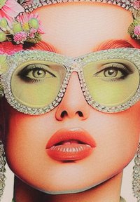 Grandes gafas de sol adornadas con lentes verdes, un marco joyado y acentos florales en la parte superior. El modelo tiene labios carnosos y cejas definidas.