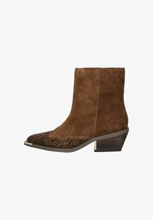 Bottine en daim marron avec un capuchon décoratif en perles, un design festonné et un petit talon empilé. La texture est douce et lisse.