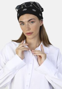 Bandana negra con patrones blancos, gafas de sol plateadas en la parte superior, y una camisa blanca de botones con un corte relajado y botones visibles. Textura suave.
