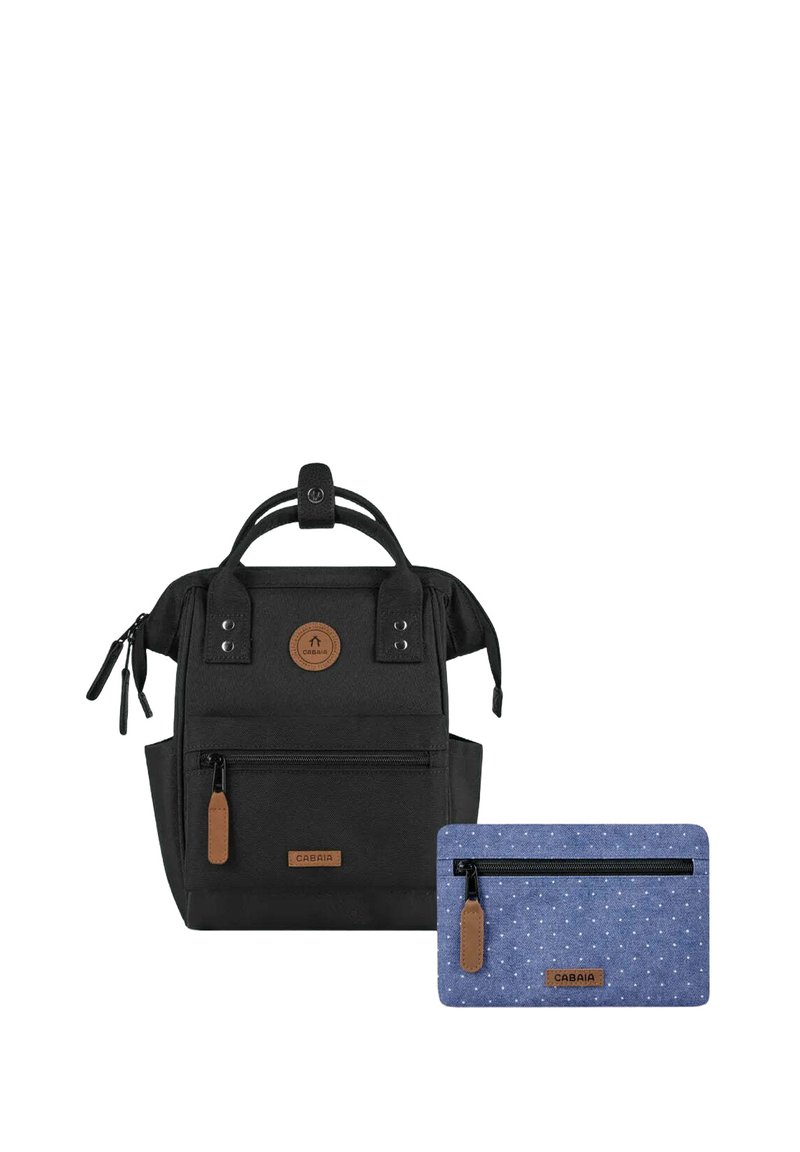 Schwarzer Rucksack aus strukturiertem Stoff mit zwei seitlichen Reißverschlüssen, einem Griff und einem braunen Logopatch. Enthält ein kleines blaues Täschchen mit weißen Punkten.