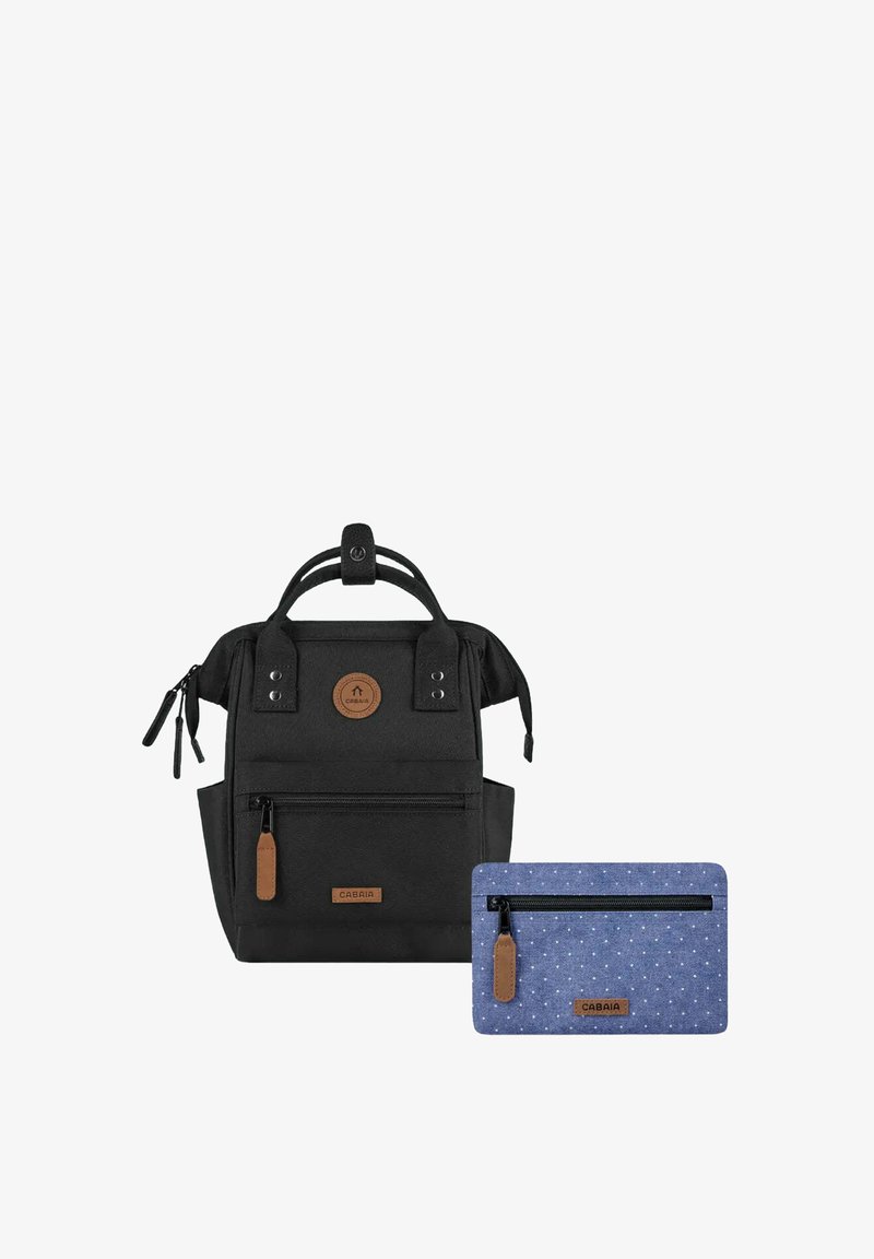 Schwarzer Rucksack aus strukturiertem Stoff mit zwei seitlichen Reißverschlüssen, einem Griff und einem braunen Logopatch. Enthält ein kleines blaues Täschchen mit weißen Punkten.