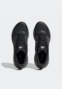 Czarne sportowe buty z teksturowaną cholewką, sznurowadłami i wyściełaną podeszwą. Zawierają trzy białe paski po każdej stronie.