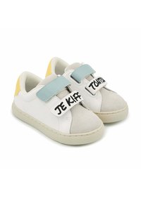 Baskets blanches et grises avec des bandes velcro, accents de talon jaunes et texte noir : "JE KIFF" et "TANTOT". Matériaux texturés et semelle en caoutchouc.