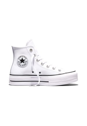 Baskets montantes blanches Converse All Star avec une bande noire sur la semelle et un patch rond visible avec le logo sur le côté.