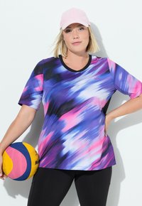 Camiseta deportiva de manga corta en un patrón abstracto de color morado, rosa y azul, con un escote negro. Se sostiene un balón de voleibol bajo el brazo.