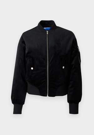 Čierna bomber bunda vyrobená z mäkkej, semišovej látky. Má predný zips, dve bočné vrecká a rebrované manžety pre priliehavý vzhľad.