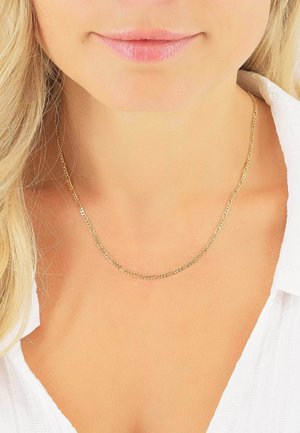 Collana in oro con link intrecciati, caratterizzata da una texture liscia e un design a strati, indossata su un collo nudo sopra un colletto bianco.