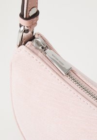 Borsa a mano in tessuto rosa con superficie testurizzata, dotata di una cerniera e accessori in argento, e di un manico in pelle per un facile trasporto.