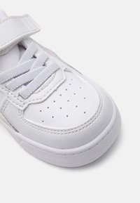 Baskets blanches avec tige en simili cuir, surface texturée, boîte à orteils perforée et fermeture à lacets. Sangle Velcro pour un ajustement sécurisé.