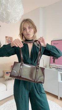 Bolso de mano de imitación cuero marrón con forma estructurada, dos asas cortas y acabado pulido. Presenta detalles cosidos y un diseño rectangular.