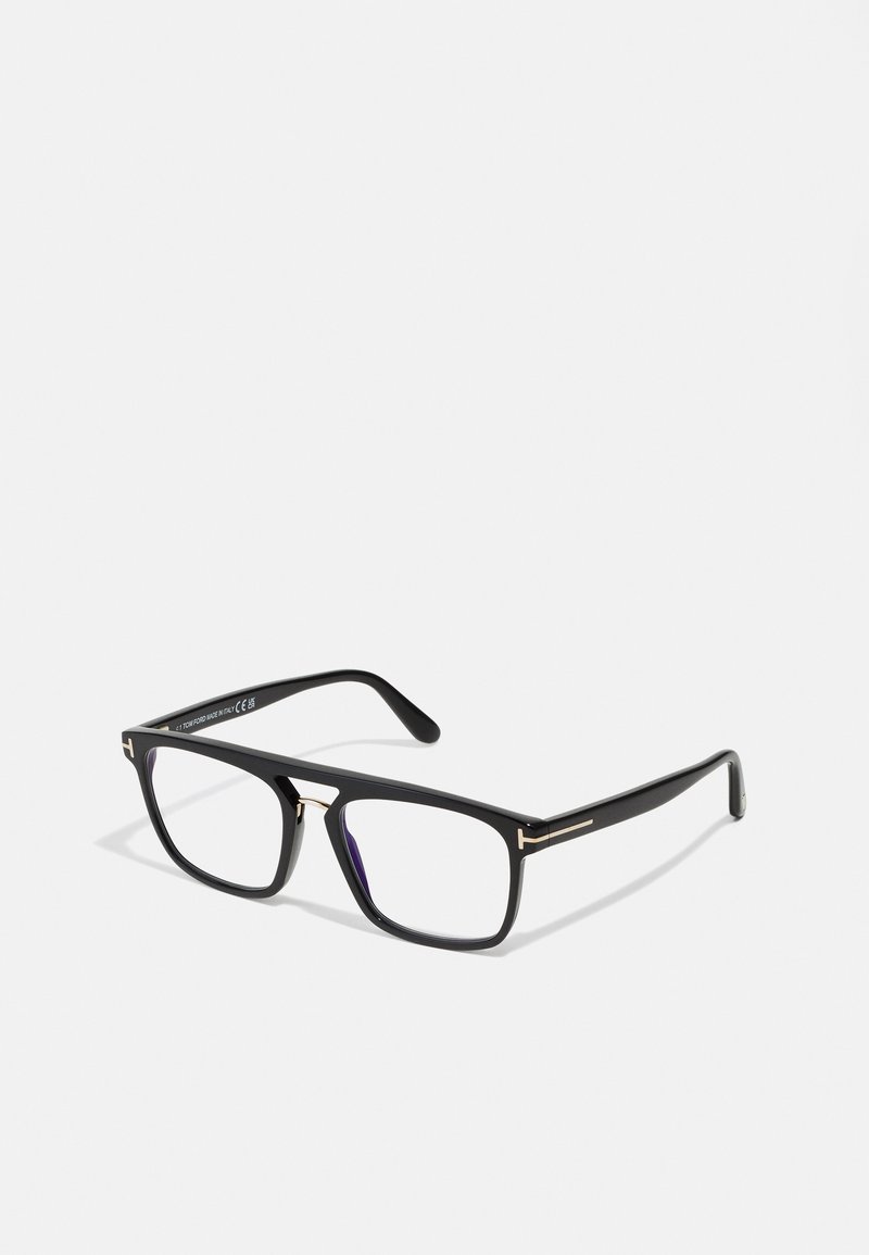 Óculos retangulares pretos com finos detalhes dourados. A armação tem um acabamento mate, com lentes transparentes e hastes suavemente curvadas.