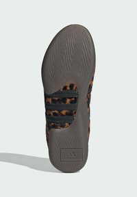 Tenisky s hornou časťou z patterned hnedo-čierneho kožúška, tromi čiernymi pruhmi a šedou gumovou podrážkou s herringbone textúrou.