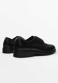 Scarpe da uomo in pelle nera con finitura liscia, punta tonda, allacciatura frontale e suola piatta in gomma bassa. Progettate funzionalmente per abbigliamento formale.