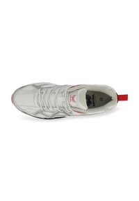 Chaussure de sport blanche avec tige en mesh, accents rouges, bout rond et semelle plate. Lacets et une sangle au talon pour un enfilage facile.