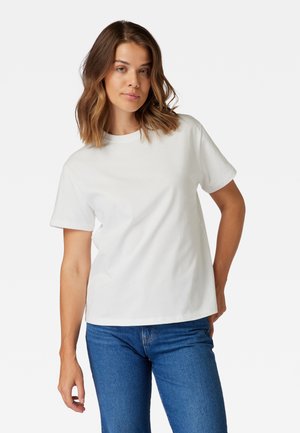 Weißes Baumwoll-T-Shirt mit Rundhalsausschnitt, kurzen Ärmeln und lockerer Passform, kombiniert mit blauen Jeans. Keine sichtbaren Muster oder Akzente.