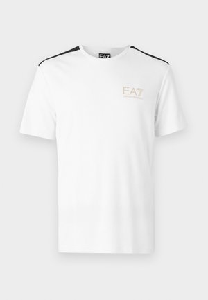 T-shirt blanc à manches courtes avec des accents noirs sur les épaules et le logo EA7 en beige clair sur la poitrine gauche. Matière en coton.