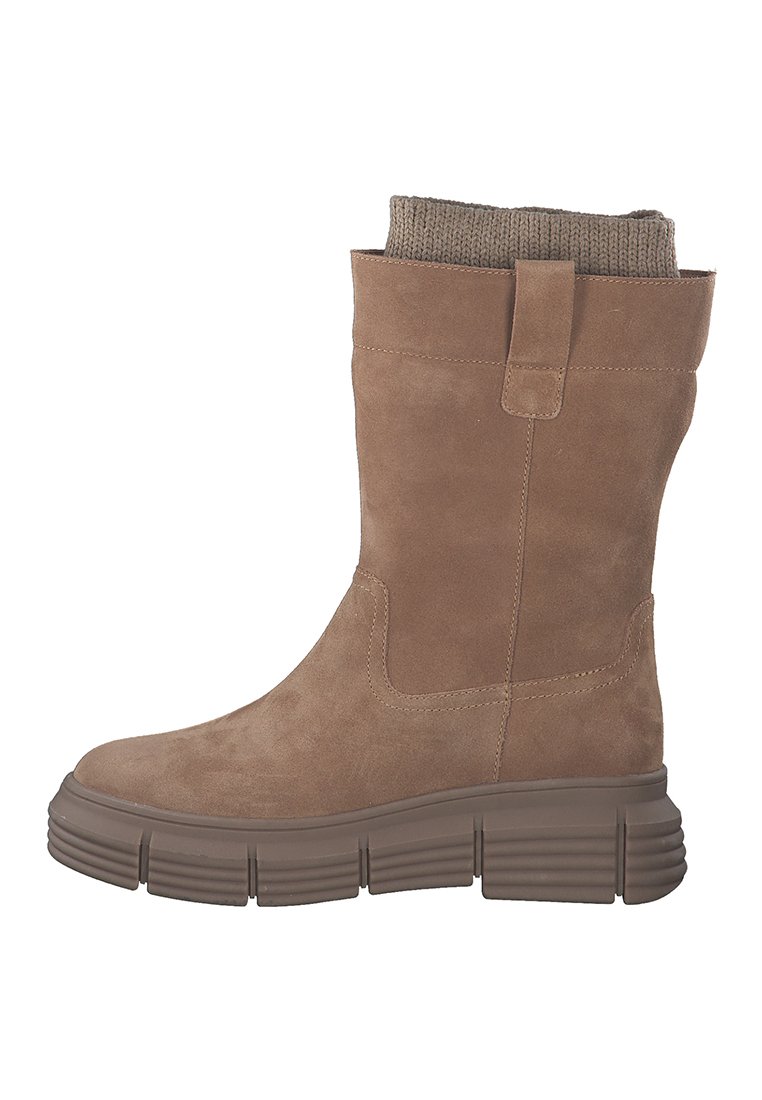 Bottine en suede marron avec un revers en tricot, semelle en caoutchouc épaisse et accents de couture minimalistes. Le design présente une forme légèrement effilée.