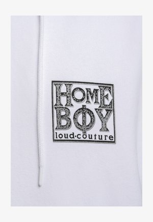 Hvit hettegenser med en svart grafisk logo som har teksten "HOME BOY loud.couture" i et rektangulært design. Jevn stofftekstur.