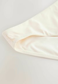 Cremfarbener, strukturierter Stoff mit glatter Oberfläche; verfügt über einen genähten Saum und eine gefaltete Kante. Geeignet für Kleidung oder Accessoires.