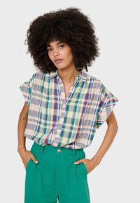 Short-sleeved button-up shirt in pastel plaid, featuring a collar and relaxed fit, paired with high-waisted green linen pants.