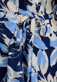 Květinové zavinovací šaty v námořnické a světle modré barvě; mají texturovanou tkaninu, pásek na zavázání v pase a abstraktní listové vzory.