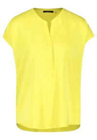 Blouse jaune à manches courtes avec un décolleté en V, confectionnée dans un tissu lisse et léger. Elle présente une coupe ample et des fentes latérales pour faciliter les mouvements.