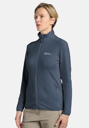 Dunkelblaue Zip-Jacke aus strukturiertem Stoff mit hohem Kragen, verfügt über ein Logo auf der linken Brust und seitliche Taschen.