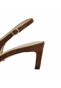 Sandale à talon haut en daim marron avec une bride arrière, une boucle dorée et un accent de talon noir contrasté. Doublure intérieure lisse.