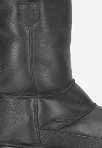 Bottine en cuir noir avec une finition texturée, présentant des coutures horizontales et une tige lisse. Construction robuste avec une semelle solide.