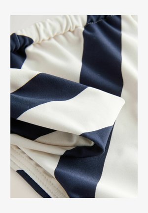 Marine en witte gestreepte stof met een gladde textuur, voorzien van een geplisseerde tailleband en contrasterende randen. De plooien tonen veelzijdigheid in het ontwerp.