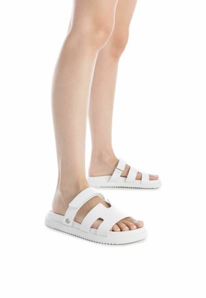 Las sandalias de playa blancas cuentan con correas dobles con acentos troquelados, suela de goma texturizada y diseño plano. Ideales para usar de forma casual en climas cálidos.