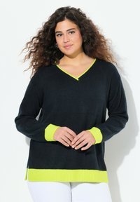 Svart v-ringad tröja med ribbad textur, med neongula ärmar och nederkant. Designen inkluderar sidoklipp för lätt rörelse.