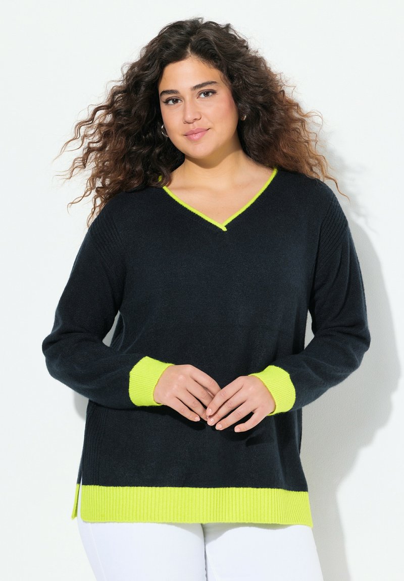 Svart v-ringad tröja med ribbad textur, med neongula ärmar och nederkant. Designen inkluderar sidoklipp för lätt rörelse.