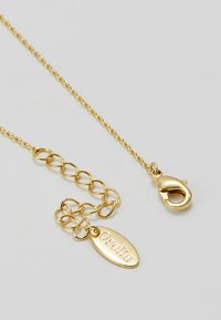 Chaîne de bijoux en ton or avec une étiquette ovale gravée "Orelia" et un fermoir à mousqueton. Comprend des maillons entrelacés, une texture lisse et une finition polie.