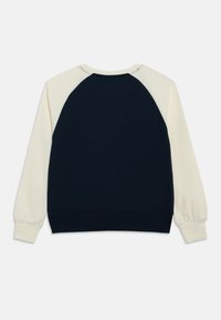 Φούτερ σε ναυτικό μπλε και εκρού με μανίκια ράγκλαν. Υλικό από βαμβάκι, ριμπ μανσέτες και τελείωμα. Απλός σχεδιασμός, χωρίς ορατά σχέδια ή μεταλλικά στοιχεία.