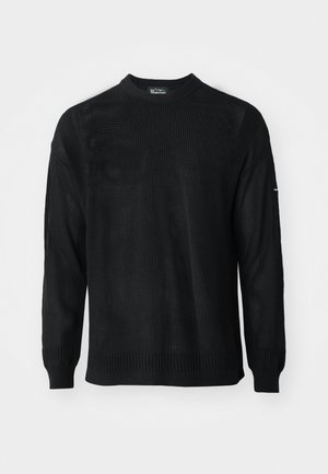 Svart strikkegenser med rund hals, lange ermer og ribbestrikkede mansjetter. Har et teksturert mønster og en avslappet passform.