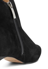 Stivaletto in suede nero con cerniera laterale, collo curvo e tacco nero opaco per un design elegante e moderno.