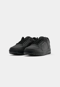 Black athletic shoes featuring a smooth synthetic upper, flat laces, padded collar, and rubber sole with textured tread for traction.