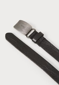 Ceinture en cuir noir avec une finition texturée, dotée d'une boucle en métal argenté rectangulaire estampillée "DIESEL" et d'une sangle lisse avec des accents cousus.